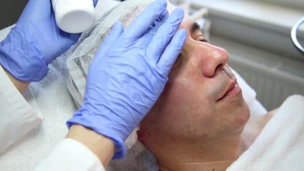 Esteticista aplica crema en la cara de los hombres — Vídeos de Stock