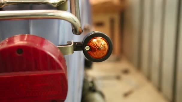Velha moto vintage está sendo reparado em uma garagem com luzes traseiras piscando — Vídeo de Stock