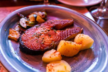 Kırmızı somon baharatlı ızgara biftek haşlanmış patates ve sebze tabakta.