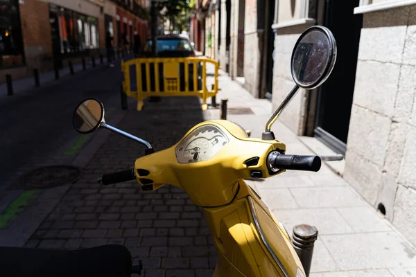 夏日的晴天，一辆黄色的老式摩托车在马德里的一条老街上缓缓前行 — 图库照片