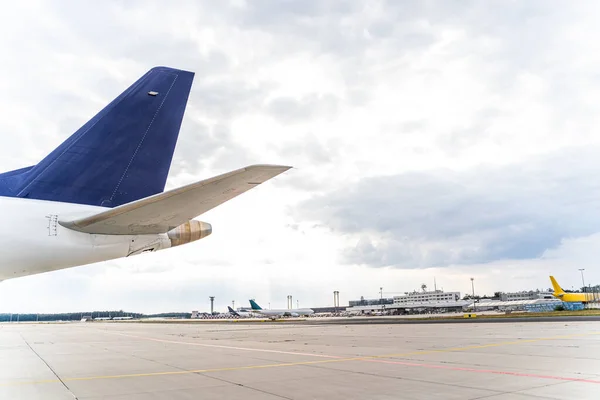 Niebieski ogon samolotu z widokiem na lotnisko i samoloty w pochmurny dzień — Zdjęcie stockowe