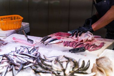 Satıcı, Barcelona 'da bir balık pazarında balık temizler ve doğrar.