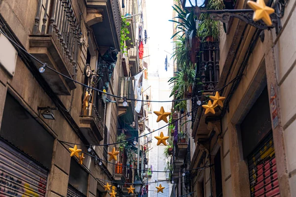 Calle estrecha con casas históricas antiguas y guirnaldas ligeras en Barcelona —  Fotos de Stock