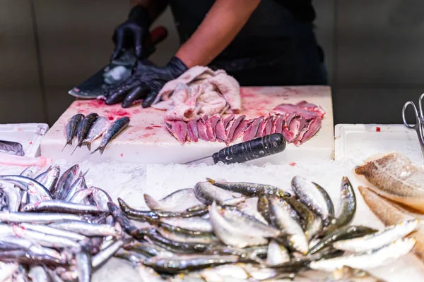 Vendedor limpia y corta pescado en un mercado de pescado en Barcelona —  Fotos de Stock