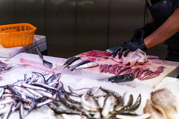 Vendedor limpia y corta pescado en un mercado de pescado en Barcelona —  Fotos de Stock