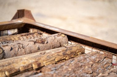 Tedavi edilmemiş ahşap kütükler dışarıda metal bir konteynırın içinde üst üste yatar.