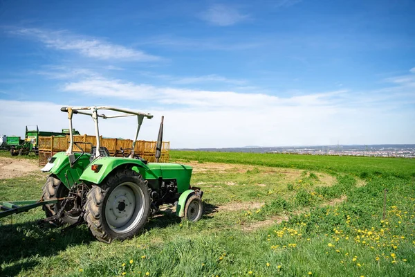 Зелений трактор стоїть на фермі в полі поблизу сільськогосподарських приладів вдень — стокове фото