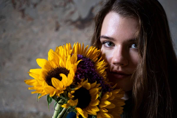 Jeune femme brune tenant un bouquet de tournesols frais à la main — Photo