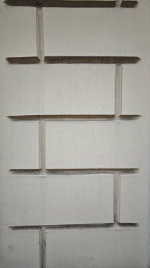 Geometrik desenli beton duvar ve yatay ve dikey yivler gösteren minimum tasarım yapısı. Görüntü, modern mimari ve soyut yapı dokusu kavramını aktarıyor.