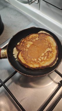 Gaz ocağında tavada pişen altın sarısı krep. Ev yapımı kahvaltı, konforlu yemek ve konforlu sabah rutini