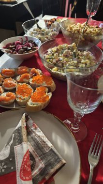 Geleneksel salatalı şenlik masası ve kırmızı masa örtüsünde servis edilen havyarlı sandviçler, cam örtüler ve tabaklar. Bayram aile ziyafeti konsepti kutlama geleneğini temsil ediyor.