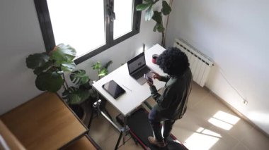 Dizüstü bilgisayarı, telefonu, kulaklığı ve tableti olan genç Afro-Amerikan bir adam küçük bir koşu bandında yürüyordu.