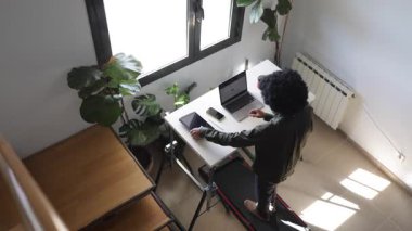 Bilgisayarlı, telefonlu, kulaklıklı genç Afro-Amerikalı adam küçük bir koşu bandının üzerinde masanın üzerinde tabletle birlikte.