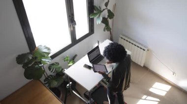 Bilgisayarlı, telefonlu, kulaklıklı genç Afro-Amerikalı adam küçük bir koşu bandının üzerinde masanın üzerinde tabletle birlikte.