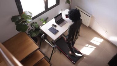 Bilgisayarlı, telefonlu, kulaklıklı genç Afro-Amerikan bir adam.