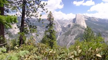 Muazzam bir dağ vadisi manzarası granit kayalıklarla çevrili, orman ağaçlarıyla çevrili. ABD Ulusal Parkı