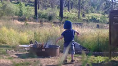 Dışarıda bir ateş çukurunun yanında oynayan genç bir çocuk..