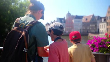 Mutlu kadın ve küçük çocuklar yazın su kenarında haritaya bakarlar.