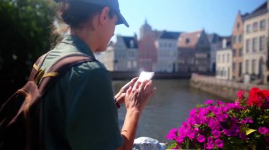 Su kenarında akıllı telefon kullanan bir kadın..