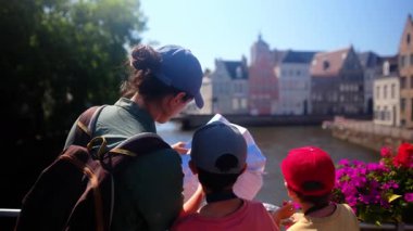 Su kenarında haritaya bakan bir kadın ve sevimli çocuklar..