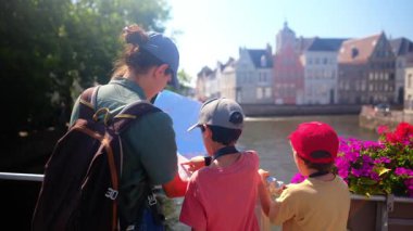 Kadın ve küçük çocuklar su kenarında haritaya bakıyorlar..