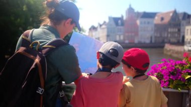 Mutlu kadın ve çocuklar su kenarındaki haritaya bakıyorlar..