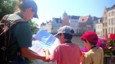 Mutlu kadın ve çocuklar su kenarındaki haritaya bakıyorlar..