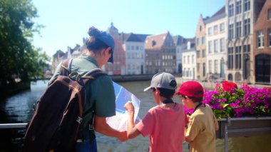 Mutlu kadın ve çocuklar su kenarındaki haritaya bakıyorlar..