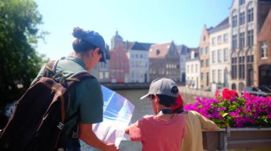 Mutlu kadın ve çocuklar su kenarındaki haritaya bakıyorlar..