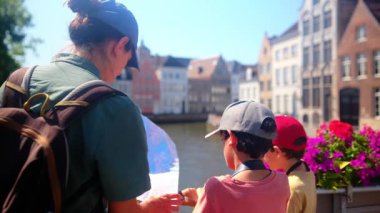 Mutlu kadın ve çocuklar su kenarındaki haritaya bakıyorlar..