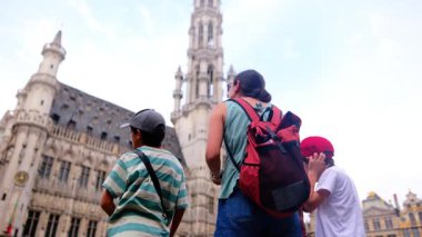 Güzel bir kadın ve küçük oğullar şehirde yürüyor.