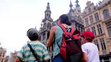 Güzel bir kadın ve küçük oğullar şehirde yürüyor.