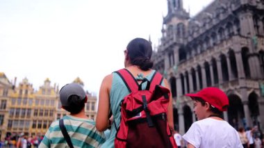 Güzel bir kadın ve küçük oğullar şehirde yürüyor.