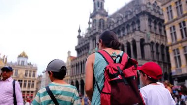 Güzel bir kadın ve küçük oğullar şehirde yürüyor.