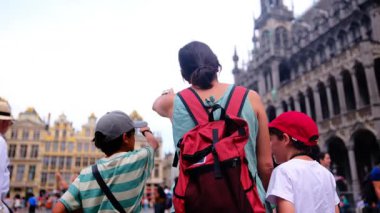 Güzel bir kadın ve küçük oğullar şehirde yürüyor.