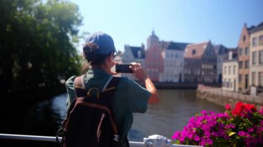 Şehirdeki deniz kenarındaki binaların yakınında fotoğraf çeken bir kadın.