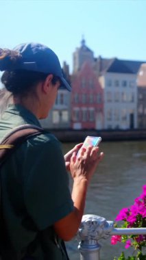 Şehirde su kenarında akıllı telefon kullanan bir kadın.