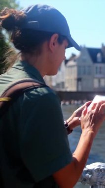 Şehirde su kenarında akıllı telefon kullanan bir kadın.