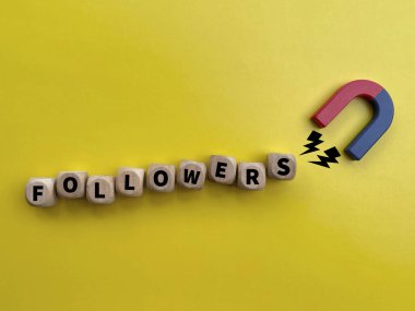 Tahta harf, sarı arka plandaki mıknatıs tarafından çekilen takipçilerini engelliyor, sosyal medya büyümesini, pazarlama stratejisini, nüfuzunu ve izleyici katılımını sembolize ediyor.