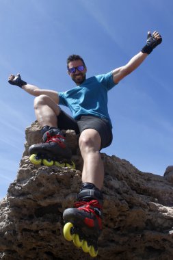 bir kayanın üzerinde gülümseyen adam paten tatil ile