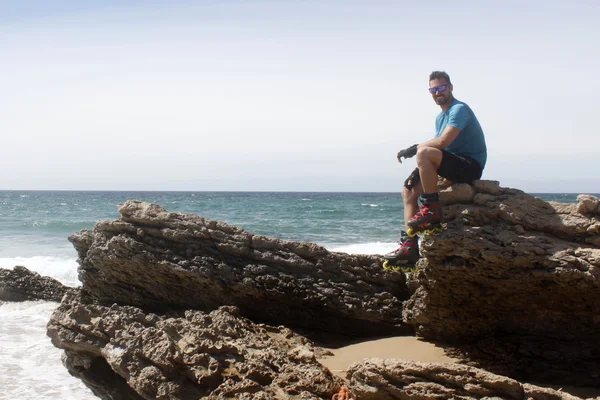 adam sahilde bir kayanın üzerinde