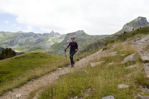 Gelukkig meisje wandelen van de bergen van de Pyreneeën, Frankrijk met haar wandelen stokken — Stockfoto