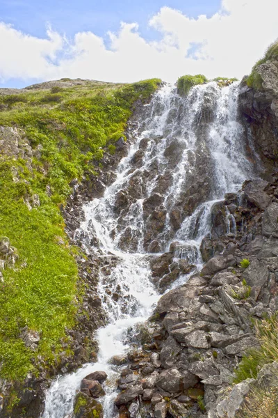 bir bulutlu, mavi gökyüzü ile bir dağ şelale
