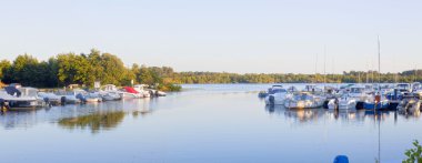 yelken ve teknelere bir gölde yansıyan ve bir iskele demirleyen