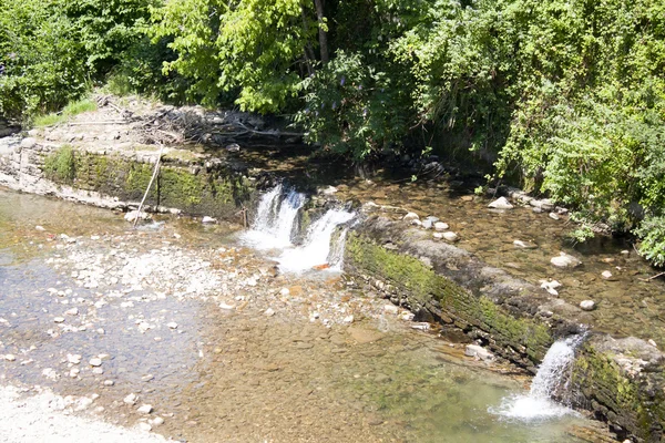 Cachoeiras em um lago na margem de um rio com pedras — Fotografia de Stock