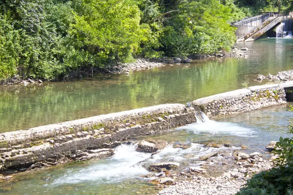 Cachoeiras em um lago na margem de um rio com pedras no verão — Fotografia de Stock