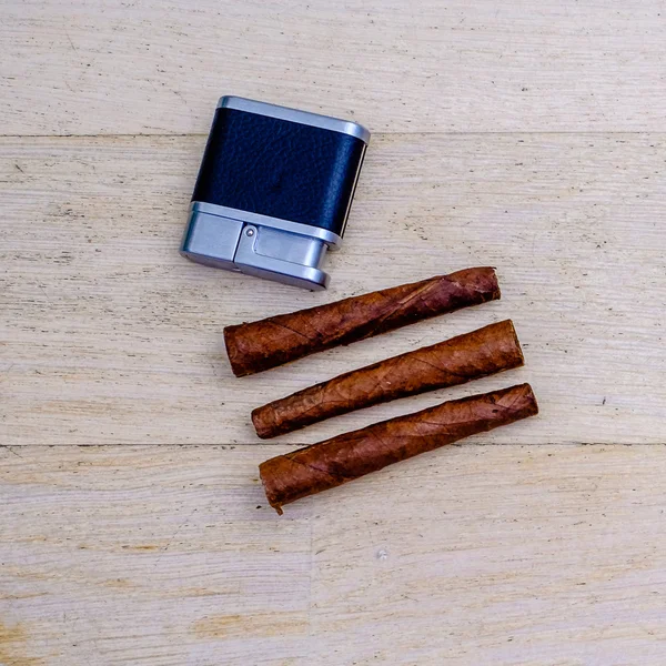 Üç Tuscan puro ve bir ahşap zemin üzerinde bir çakmak