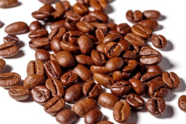 Beyaz arkaplanda paket tasarımı elementleri olarak izole edilmiş taze kahve çekirdekleri yığını.