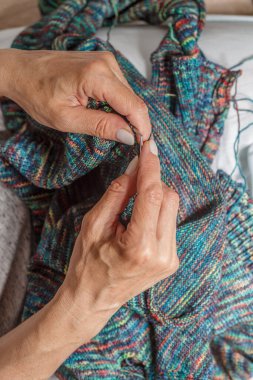 Yün ipliği kullanarak telli el yapımı giysiler ören tanınmamış bir kadının ellerine yakın durun. Boş zaman etkinliği kavramı. İplikten örgü örmek..