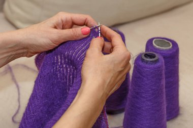 Yün ipliği kullanarak telli el yapımı giysiler ören tanınmamış bir kadının ellerine yakın durun. Boş zaman etkinliği kavramı. İplikten örgü örmek..